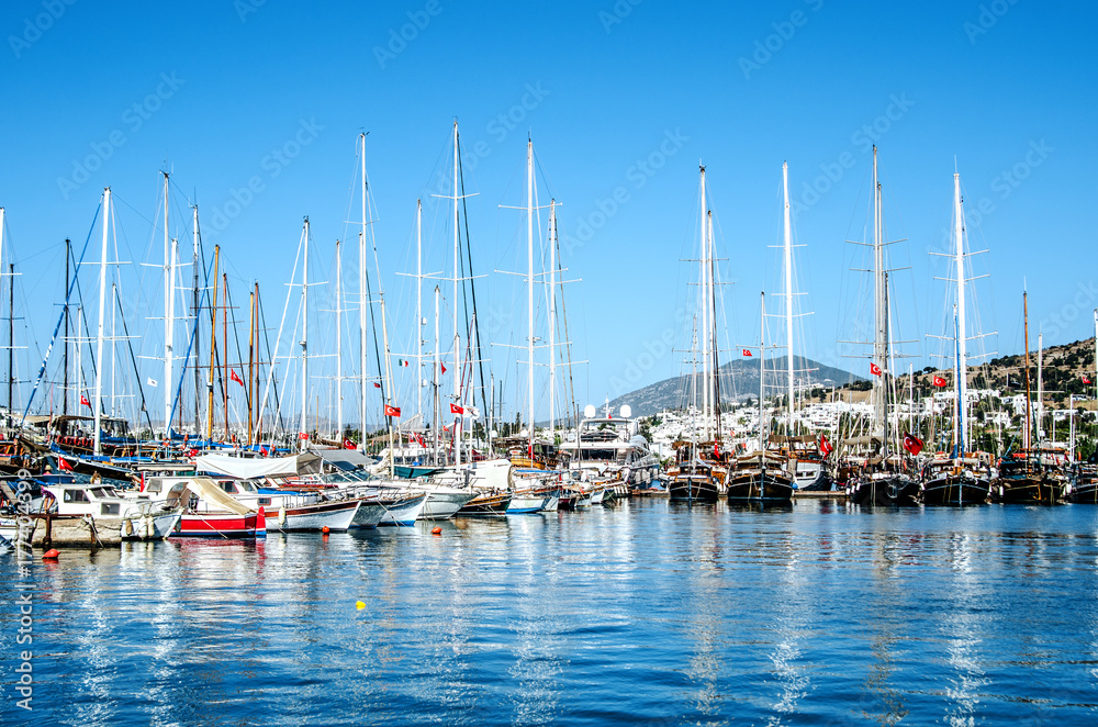 Large and small beautiful yachts are reflected in the sea water in the port of Bodrum, Turkey.