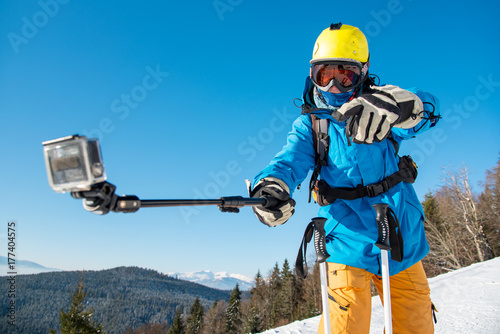 Horizontal shot of a male skier having fun outdoors taking a selfie with action camera on a monopod modern technology active lifestyle concept