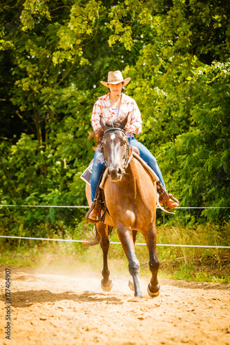 Cowgirl doing horse riding on countryside meadow