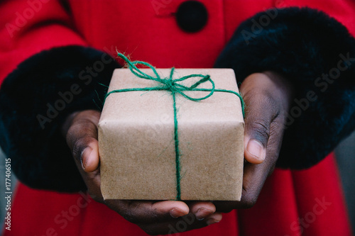 African American girl's hand in red coat holding a wrapped present