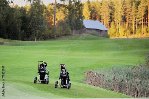 Two golf bags on golf course in Finland. Barn on the background.