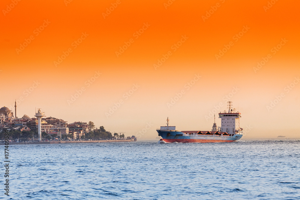 Empty container cargo ship in Istanbul Bosporus harbor at sunset