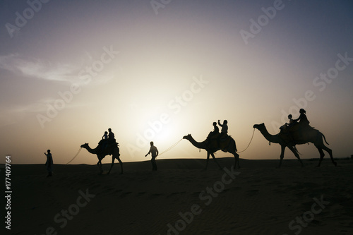 Silhouette of tourist enjoying a camel ride in the desert of Rajasthan, India. photo