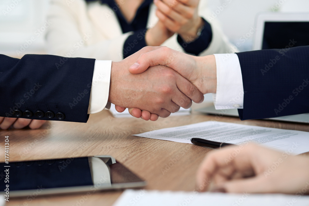 Close up of business people shaking hands at meeting or negotiation in the office. Partners are satisfied because signing contract