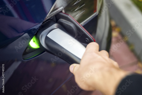 Man's hand holding modern electric car charger outlet.