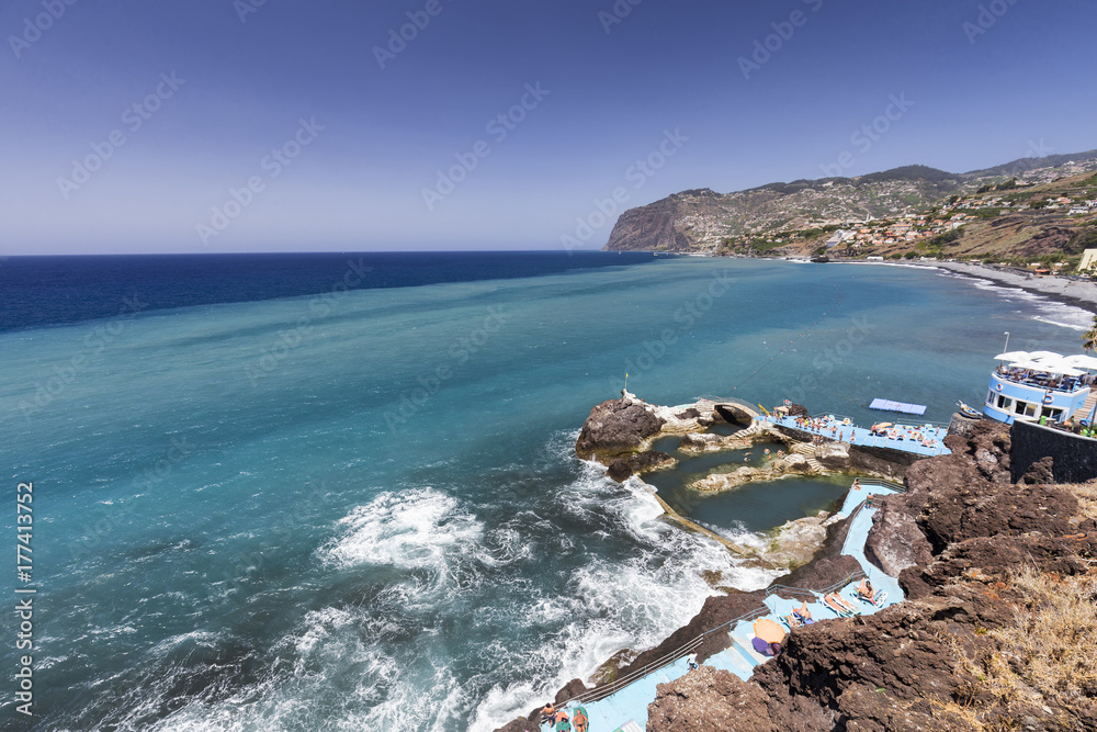 Different colored waters behind ocean water pools in Sao Martinho on the island of Madeira, Portugal.
