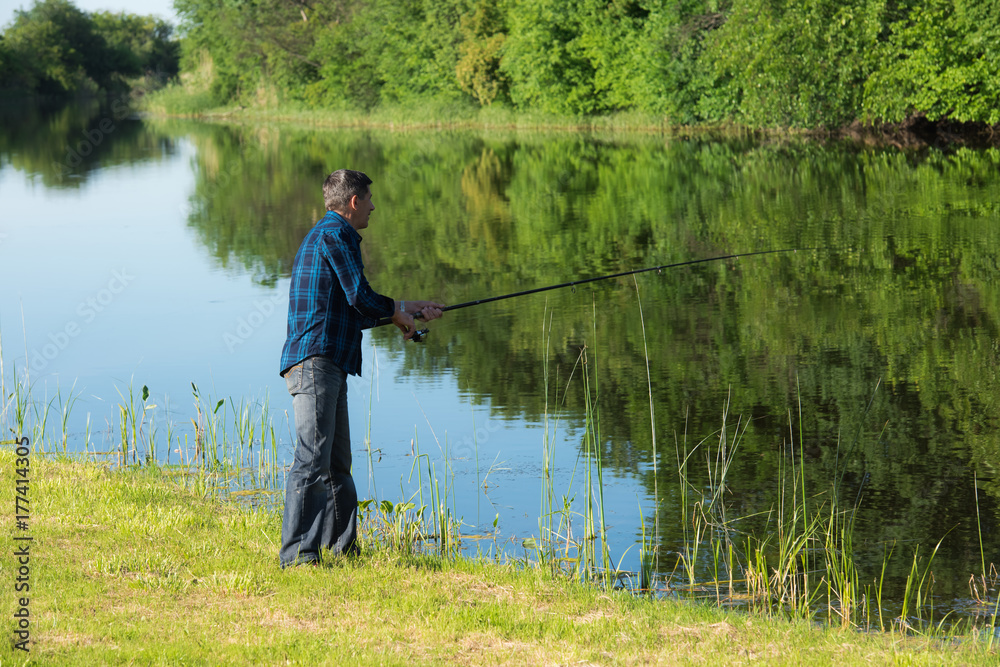 Retired active man is fishing at the river bank Retired active man is fishing at the river bank