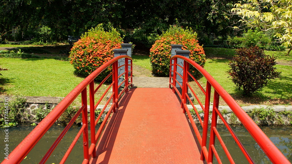 rote Brücke führt zentral in einen Park rote Brücke führt zentral in einen Park