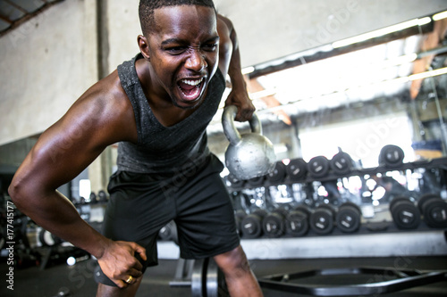 Close up of male athlete bodybuilder active lifting a kettlebell, emotion, intensity, determination