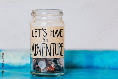 Money saving in jar with label saying
'let's have an adventure'