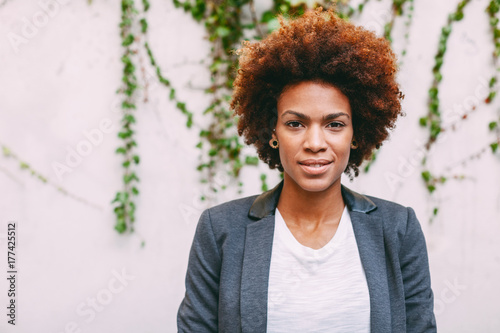 Portrait of afro american woman standing on ivy wall.