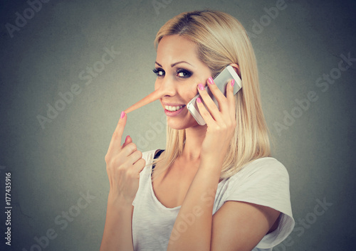 Happy young liar woman with long nose talking on mobile phone