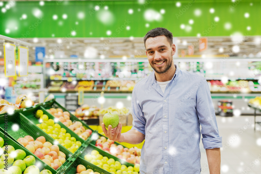 happy man buying green apples at grocery store
