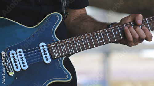 A Musician Plays a Blue Electric Guitar photo