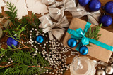 Christmas flat lay composition of fir branches with gift box and decorations on the brown wooden background.