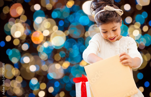smiling little girl with gift box over lights