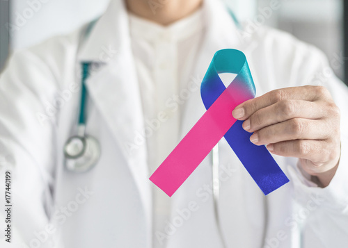 Thyroid cancer awareness ribbon in Teal Pink Blue symbolic bow color in doctor's hand to support patient with tumor illness photo