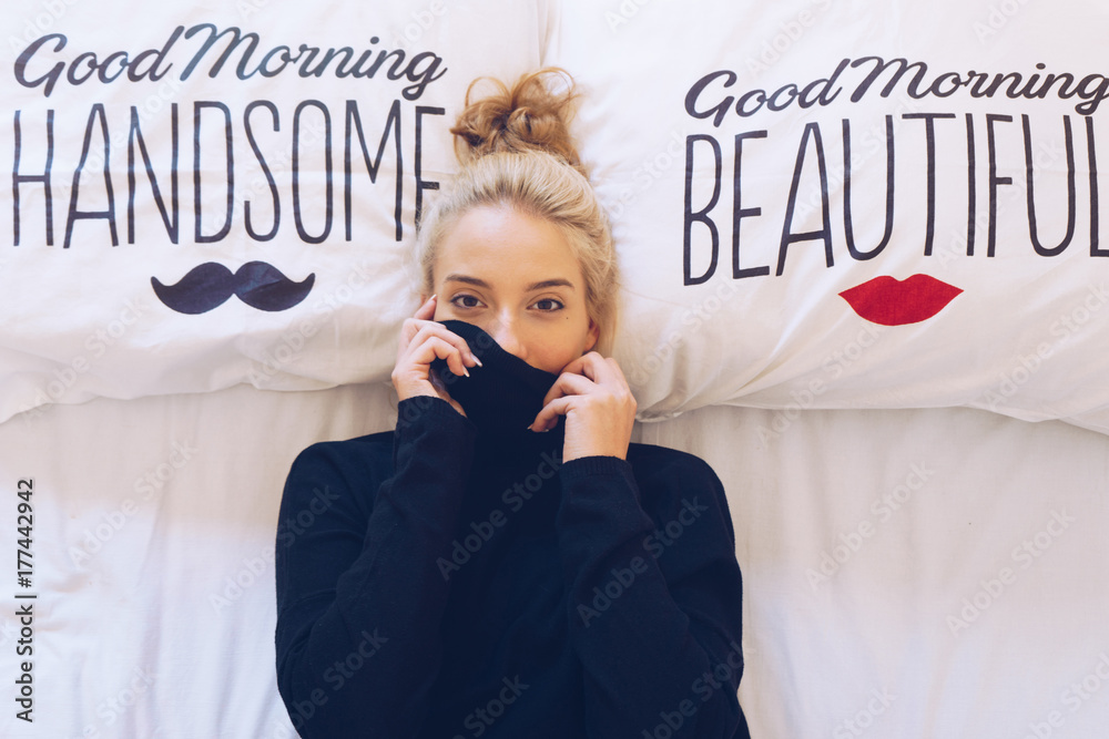 Fototapeta premium Playful woman lying in bed while hiding her face
