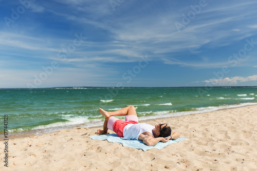 happy smiling young man sunbathing on beach towel