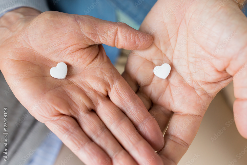 close up of couple hands with heart shaped pill close up of couple hands with heart shaped pill