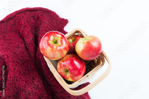Red apples in a basket with a cozy blanket on a white background