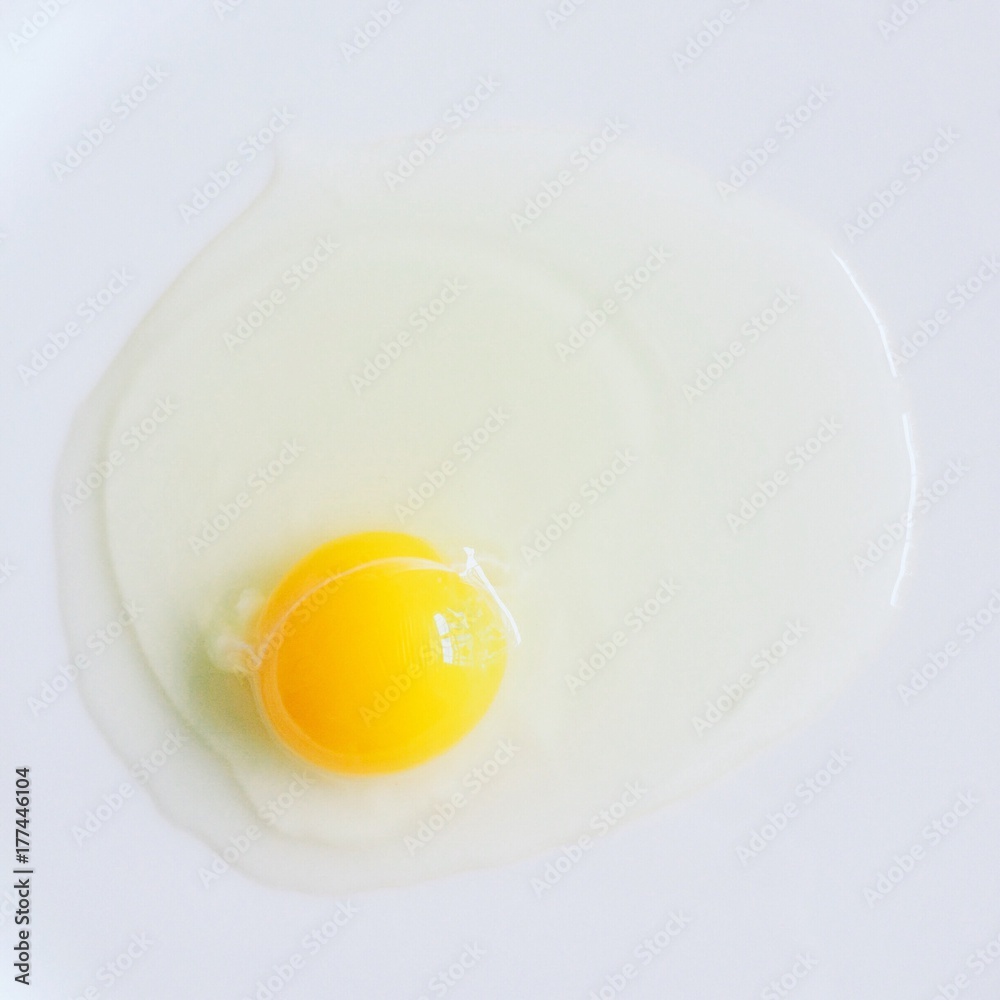 A single raw egg and yolk on a while table A single raw egg and yolk on a while table
