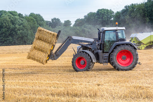 Schwarzer Traktor transportiert Strohballen, Seitenansicht