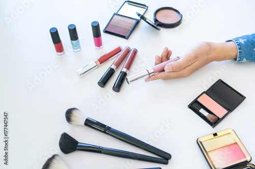 Many makeup cosmetics different on white wooden table background, top view