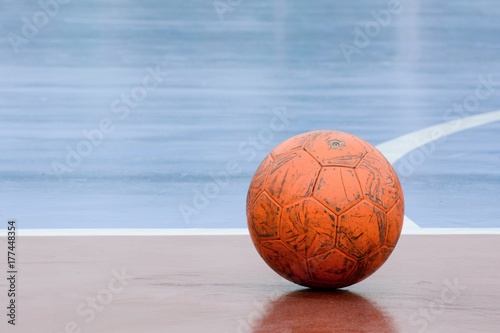 Canvas Print old and damaged orange ball at futsal court