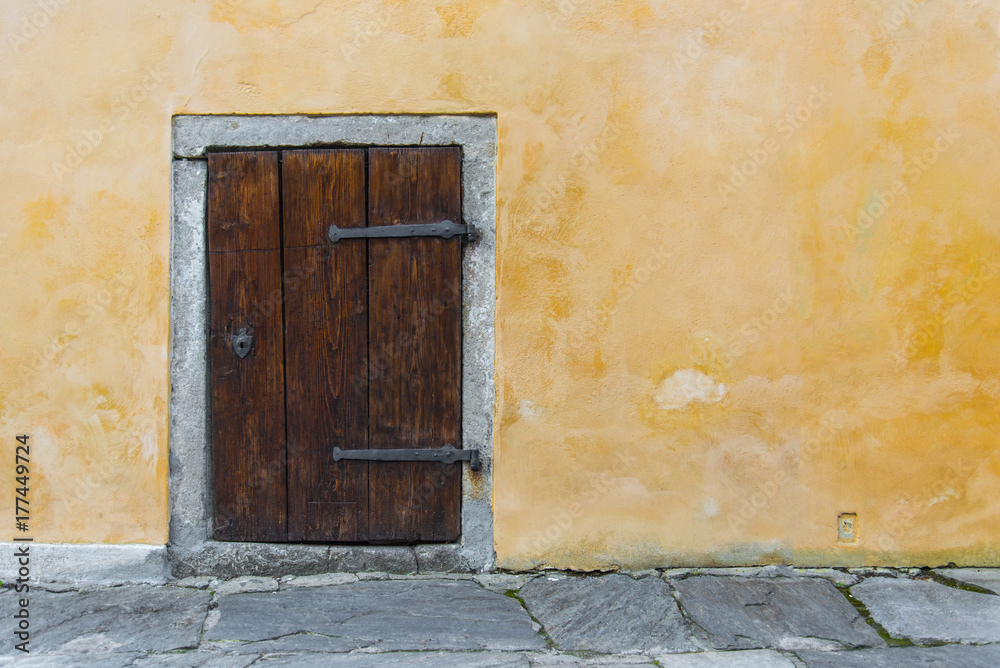 Old wooden small door on the yellow rustic wall Old wooden small door on the yellow rustic wall
