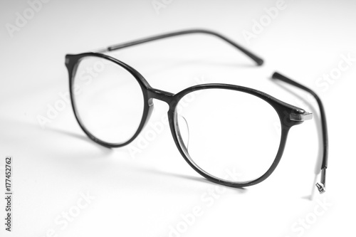Old glasses on broken legs on white background,selective focus
