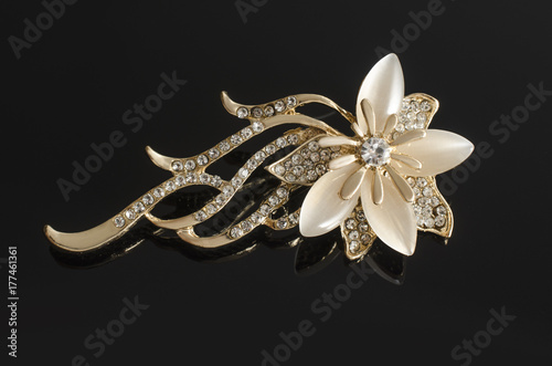 gold brooch flower with gems and moon stone isolated on black