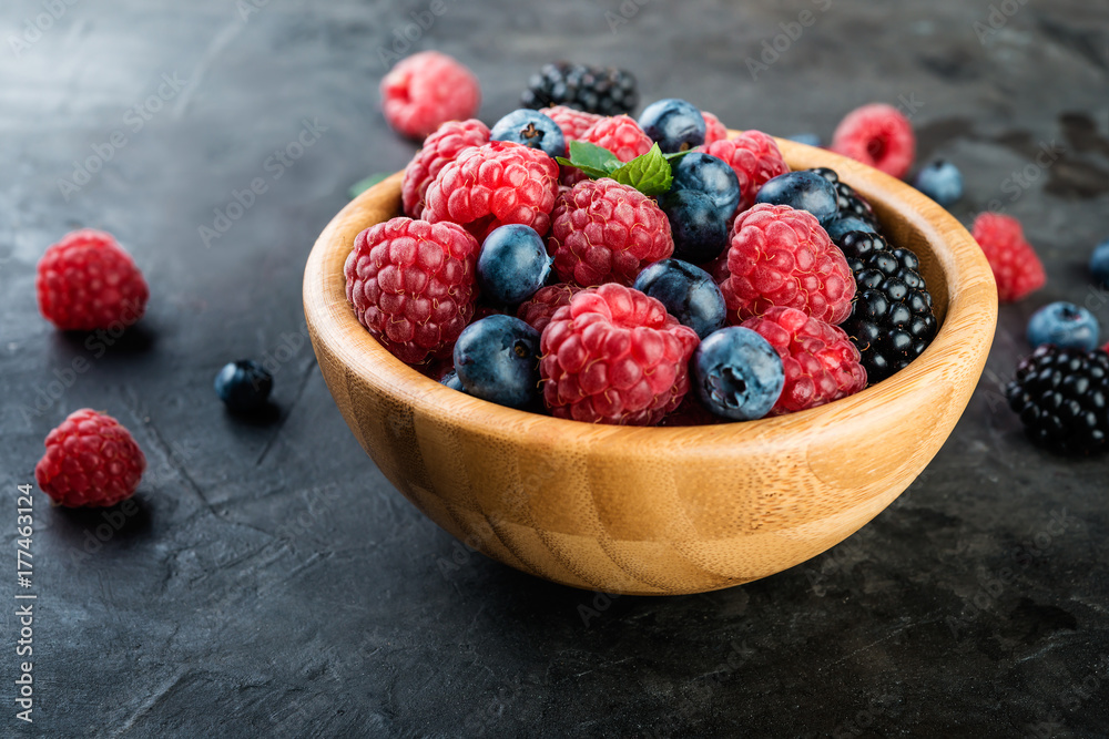 Fresh berries in a bowl on dark background close up Fresh berries in a bowl on dark background close up