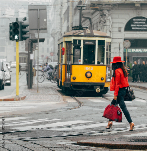 Fashionable Italian woman in Milan, Italy crossing street with traditional Milanese tram in background photo