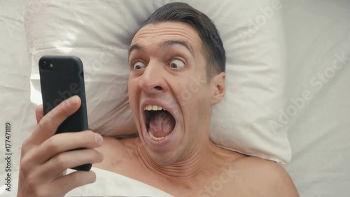 young man wakes up in the morning in bed and gets scared that he overslept to work