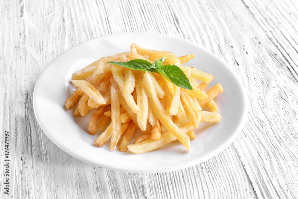 Plate with yummy french fries on wooden table