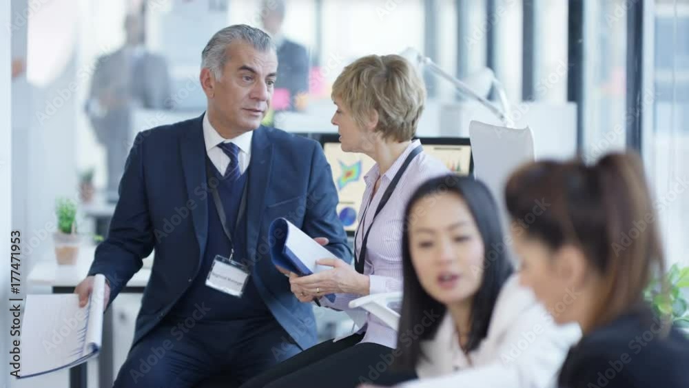 Business managers at a training seminar looking at paperwork & discussing Business managers at a training seminar looking at paperwork & discussing