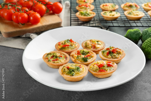 Plate with broccoli quiche tartlets on table