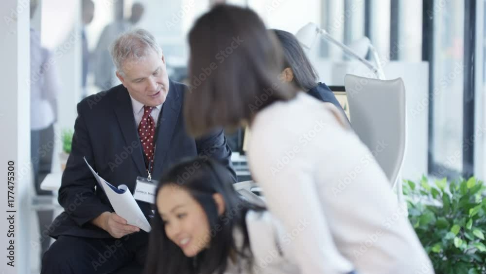 Business managers at a training seminar looking at paperwork & discussing Business managers at a training seminar looking at paperwork & discussing