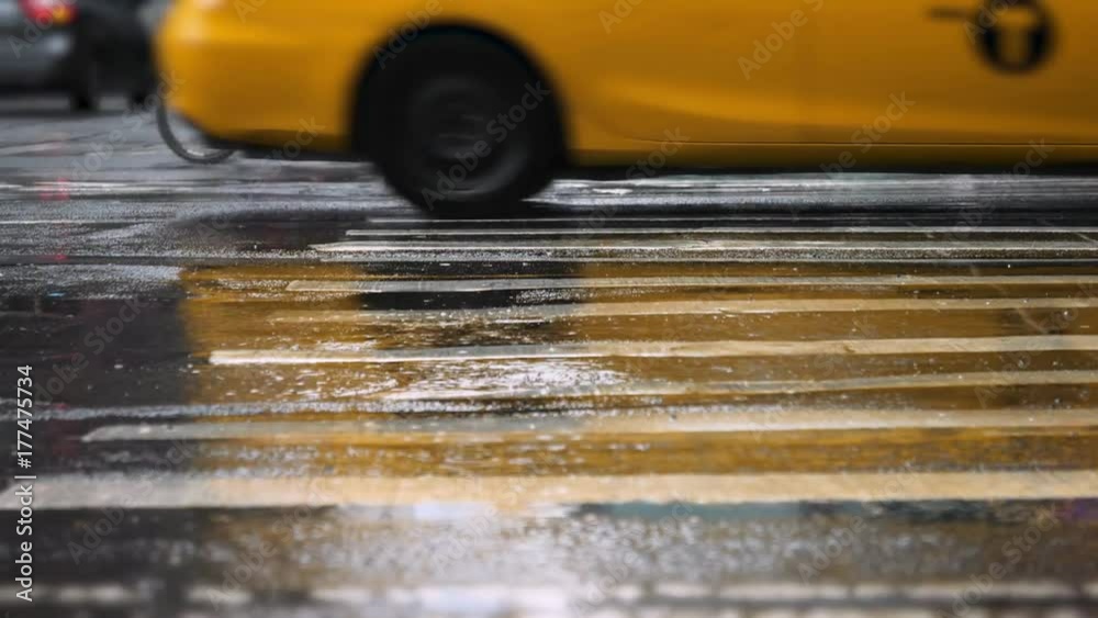 A low angle slow motion view of traffic on a rainy Manhattan street.  	
