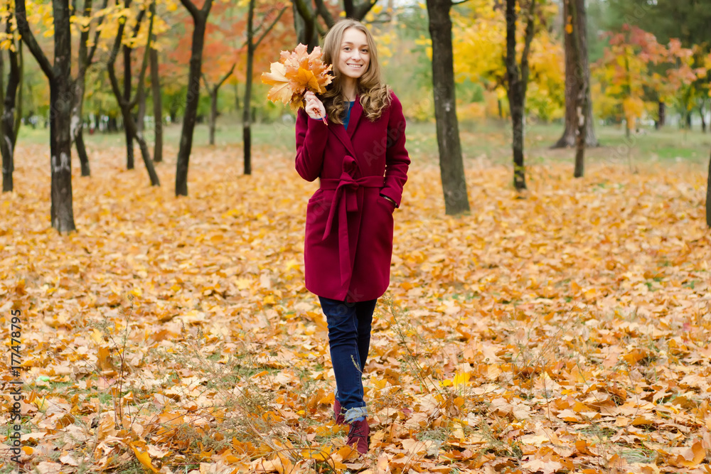 Woman in a coat bouquet of orange leaves in hand Woman in a coat bouquet of orange leaves in hand