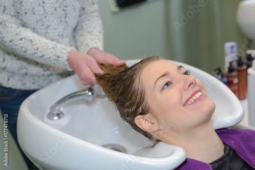 happy woman is getting a hairwash by a hairdresser