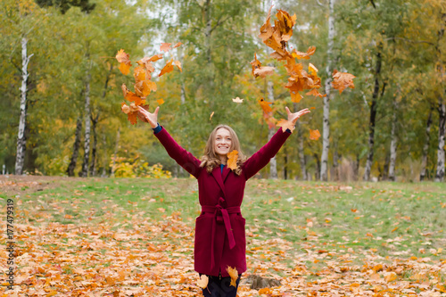 Beautiful woman in a coat park autumn leaves fly