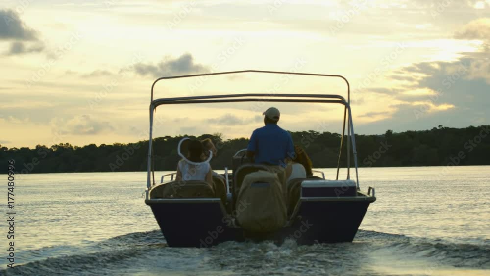 Tourists on African vacation take boat trip down the Zambezi river at sunset