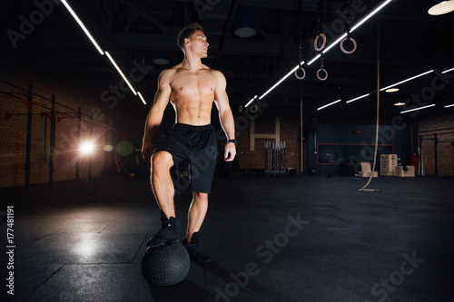 Confident muscled man doing push up from MEDICINE ball in gym.