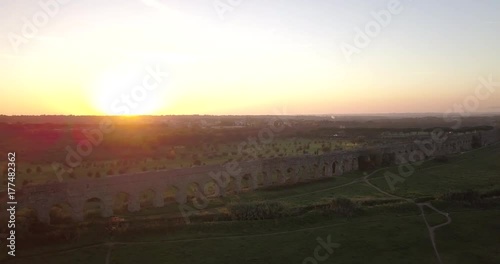 Video from above. Aerial view of the ancient Roman Aqueduct at sunset. Old ruins surrounded by a green public Park. Rome, Italy. photo