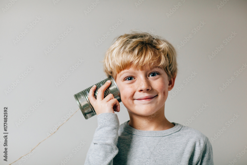 smiling boy plays with a tin can phone smiling boy plays with a tin can phone