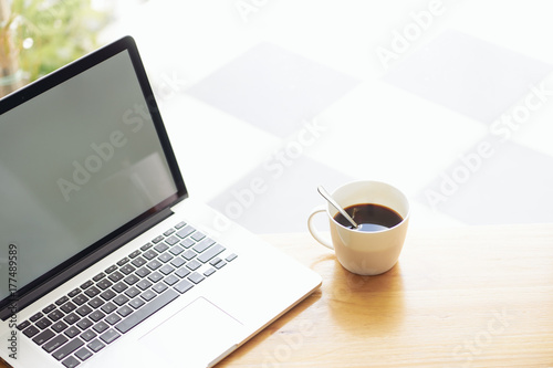 Laptop and coffee on wooden table .