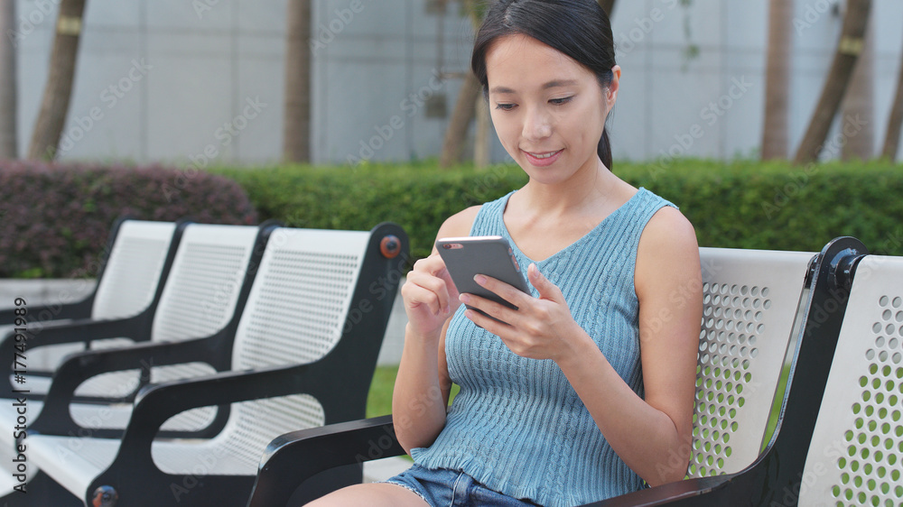Woman use of mobile phone and sitting at outdoor