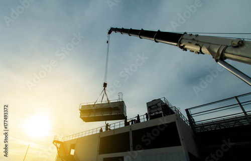 mobile crane lifting Cooling machine, silhouettes at sunset photo